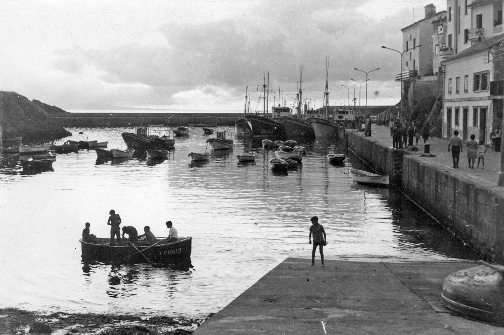 Niños remando en un chalano en el muelle de Tapia