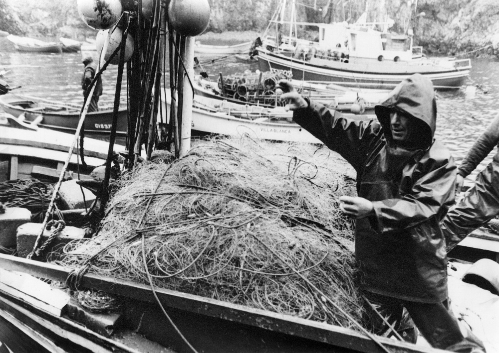 Pescador en su lancha preparando las redes para pescar en el muelle de Tapia de Casariego