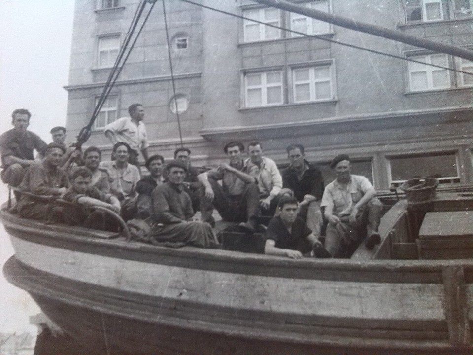 Grupo de marineros en un barco varado en tierra en el muelle de Tapia de Casariego, Asturias