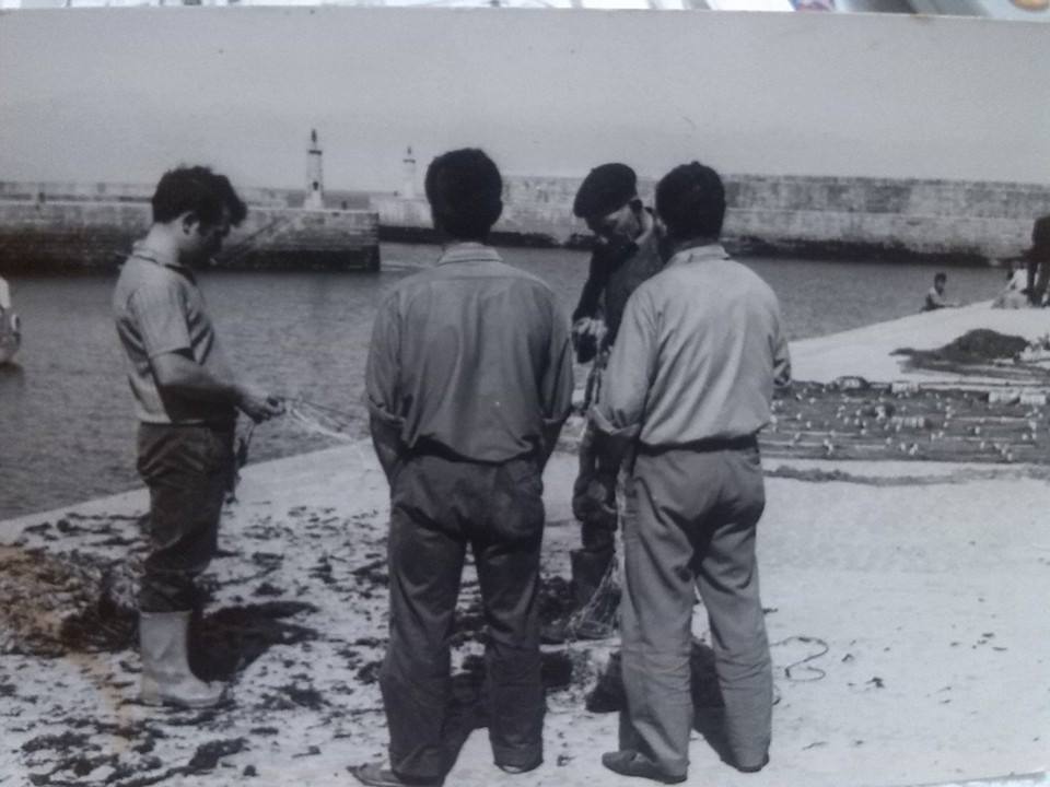 Grupo de marineros en el muelle de Tapia de Casariego reparando sus redes