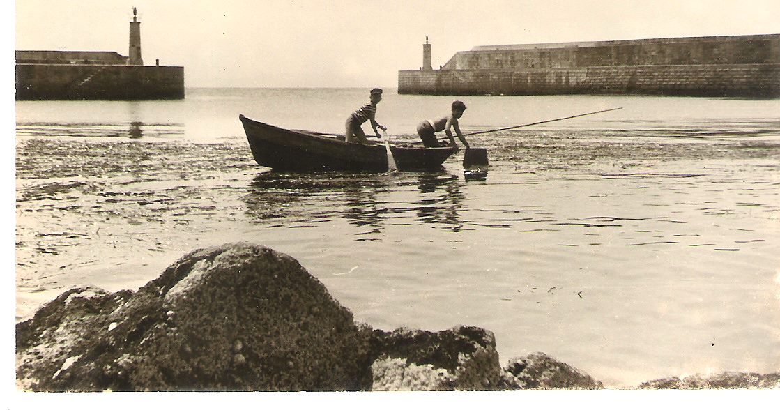 Niños en chalano pescando en el muelle de Tapia