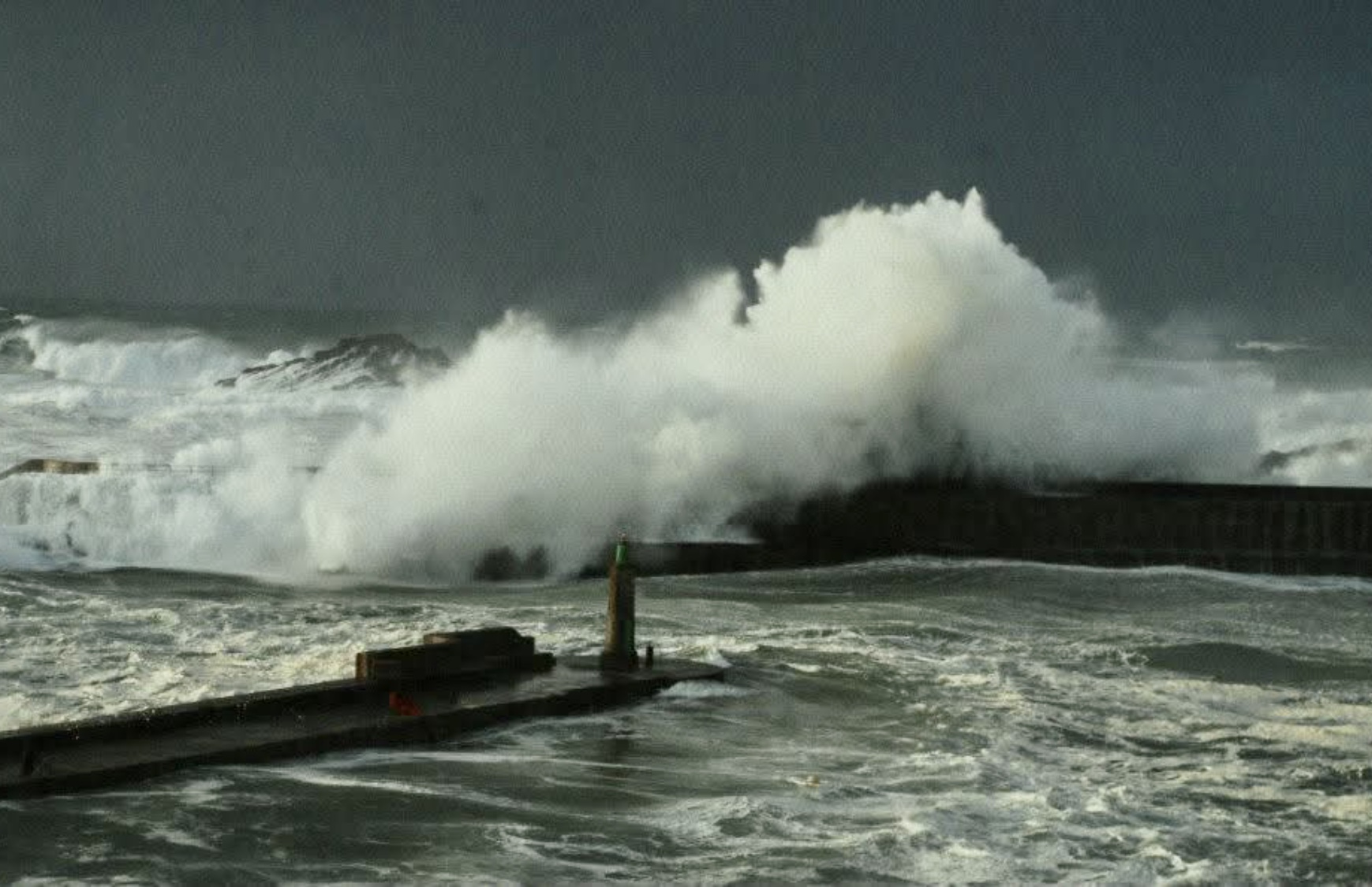 Ola estrellandose con fuerza sobre el faro rojo en Tapia de Casariego
