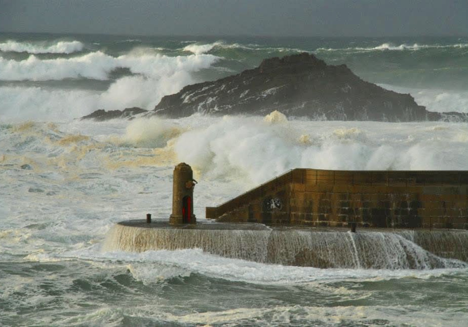 Marejada golpeando sobre el faro rojo