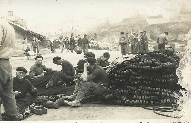 Marineros reparando las redes en el muelle