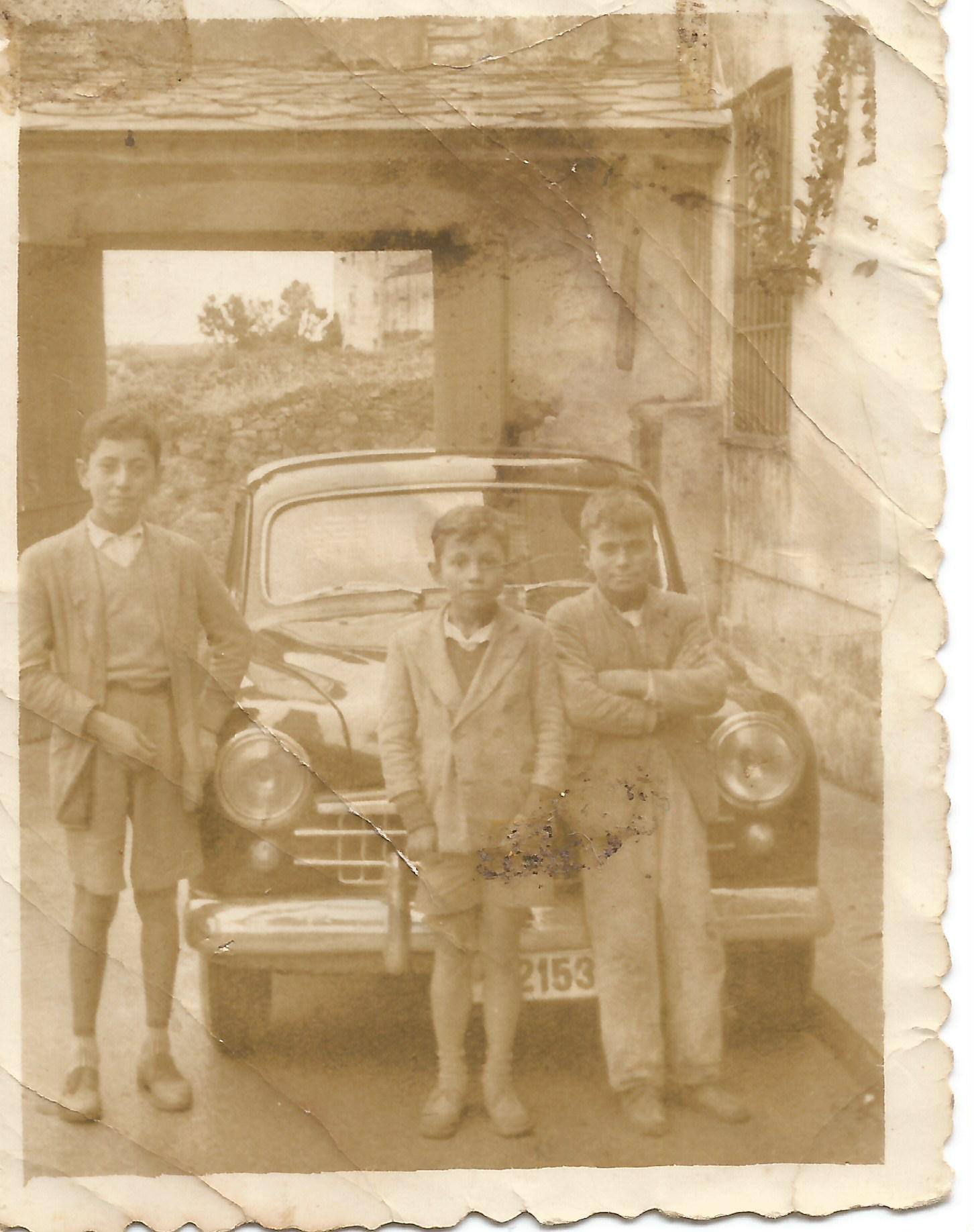 Niños apoyados en un coche